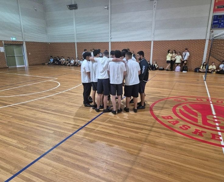 An Image of a group of students in a huddle during half time of a basketball game.