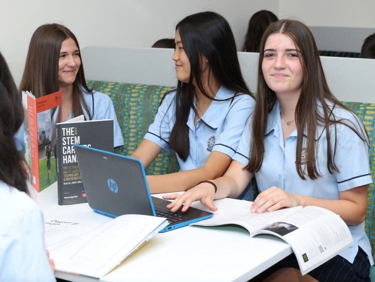 Girls sitting in the booths in the study area with their textbooks, books and laptops.