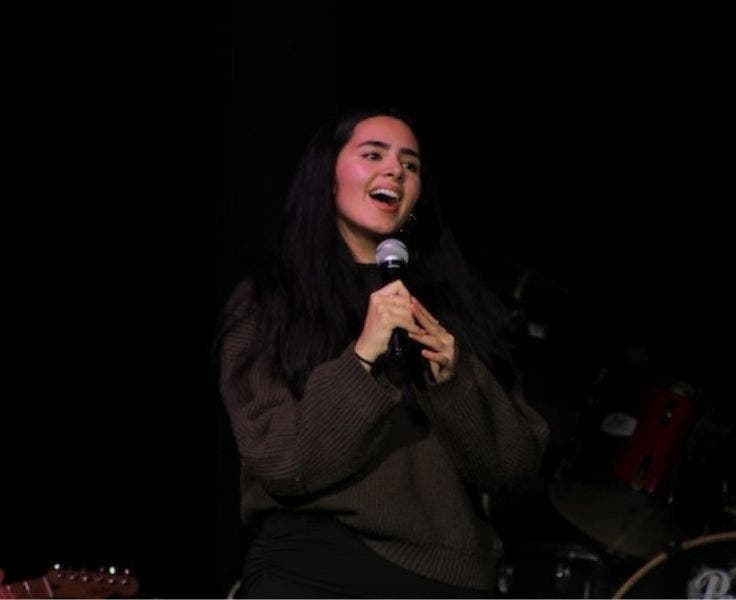 An image of a student signing on stage performing for the school.