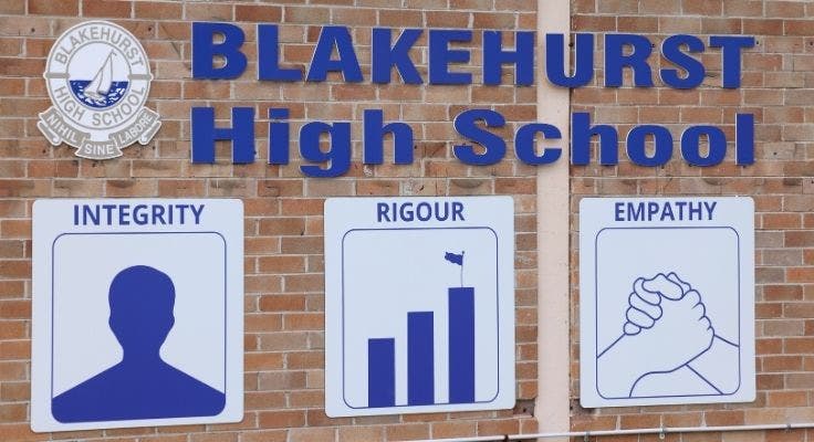An image showcasing the school building prominently displaying signs that illustrate the values of Integrity, Rigour, and Empathy.