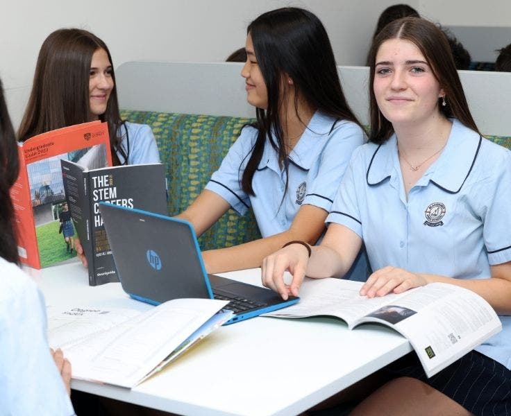 An image of students at a booth with their textbooks, workbooks and latops studying