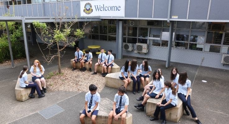 An image of students sitting on the stone seats below our welcome sign.
